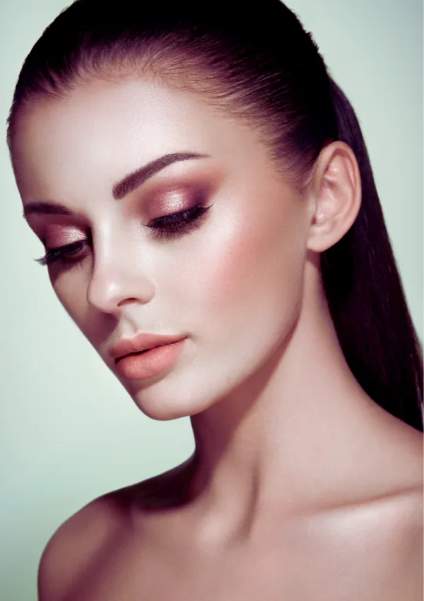 Donna che applica l'highlighter sul viso, evidenziando un aspetto luminoso e naturale con una pelle radiosa.